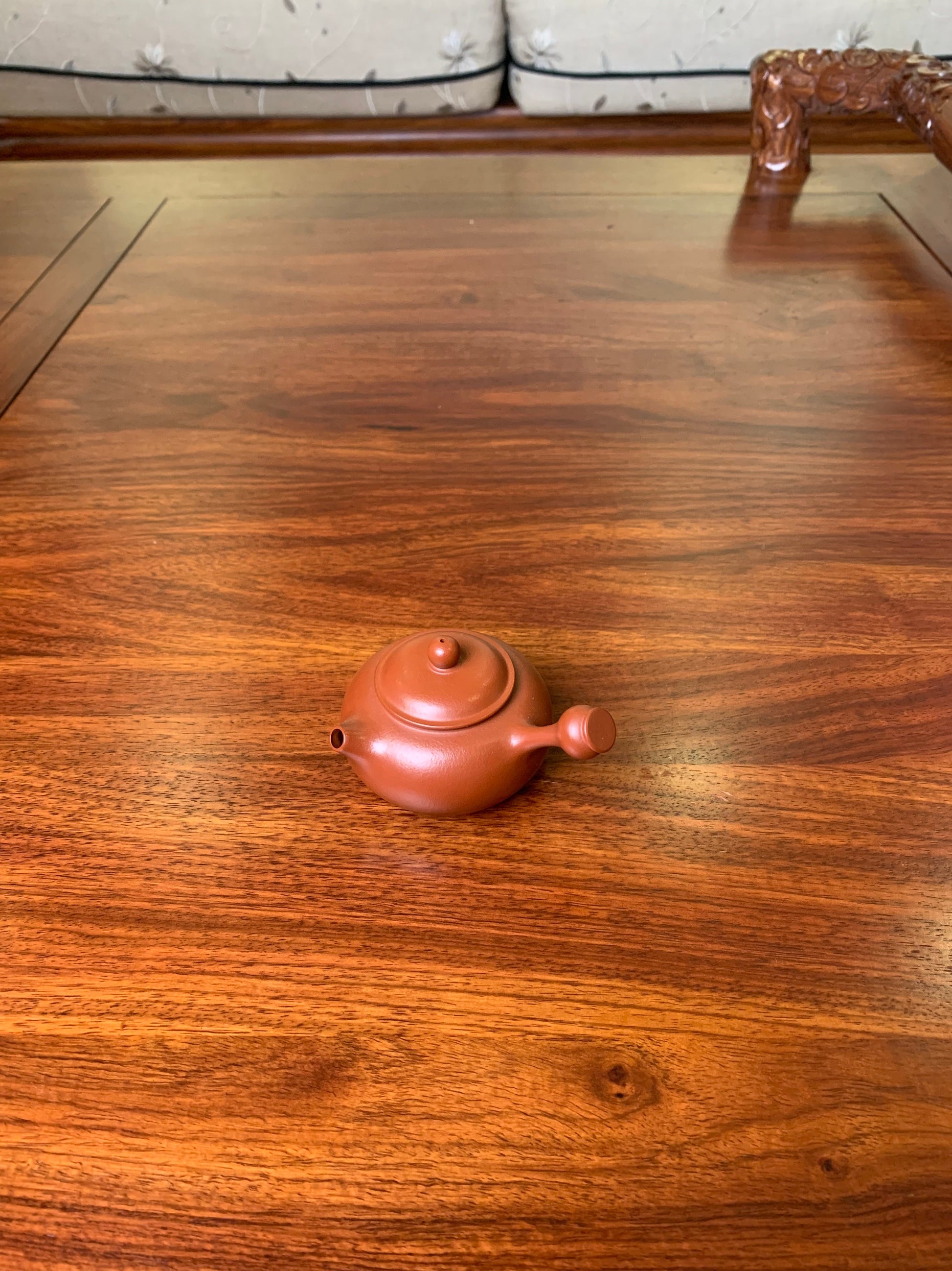 Small teapot on the table, handmade from purple clay lid