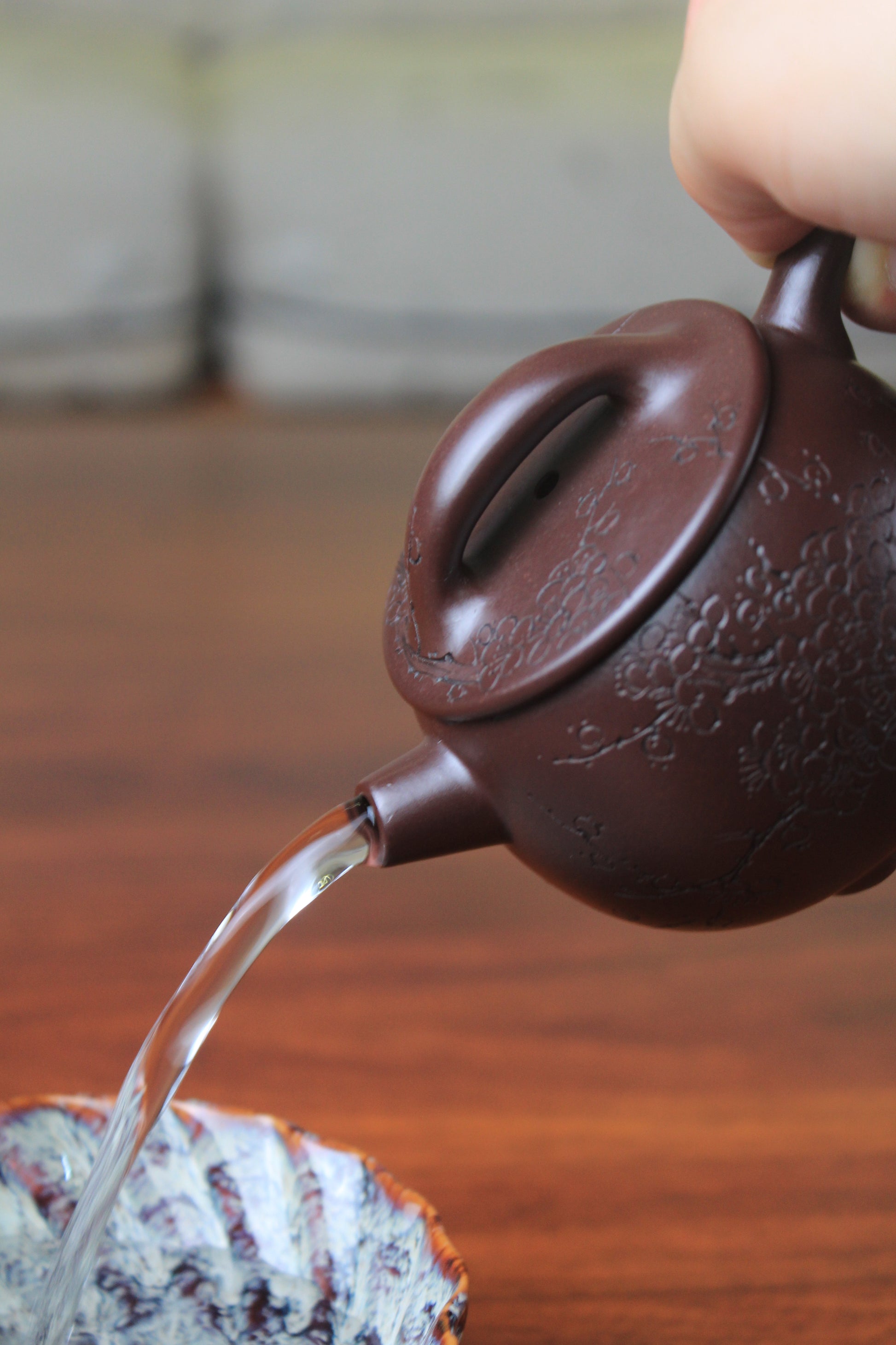 pour of the cute chinese teapot handmade with purple clay on the table