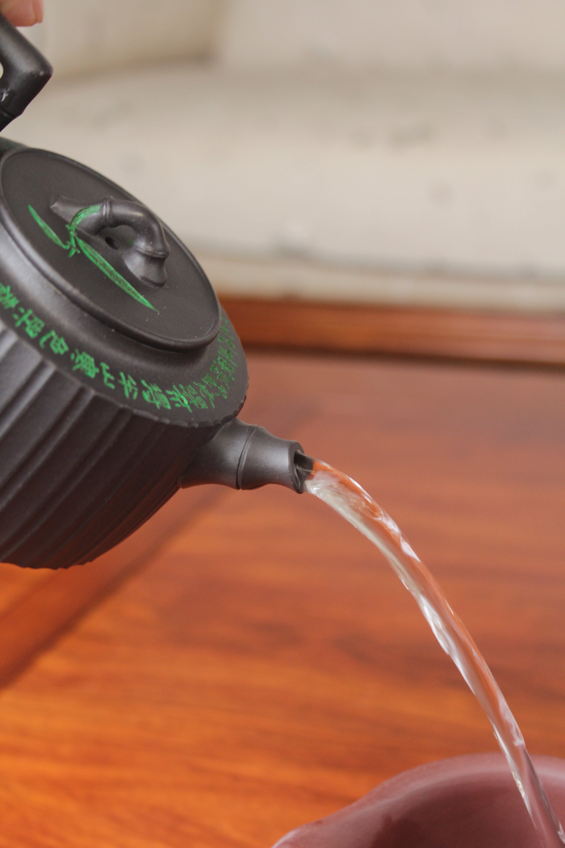 Pour of the vintage teapot handmade with purple clay on the table