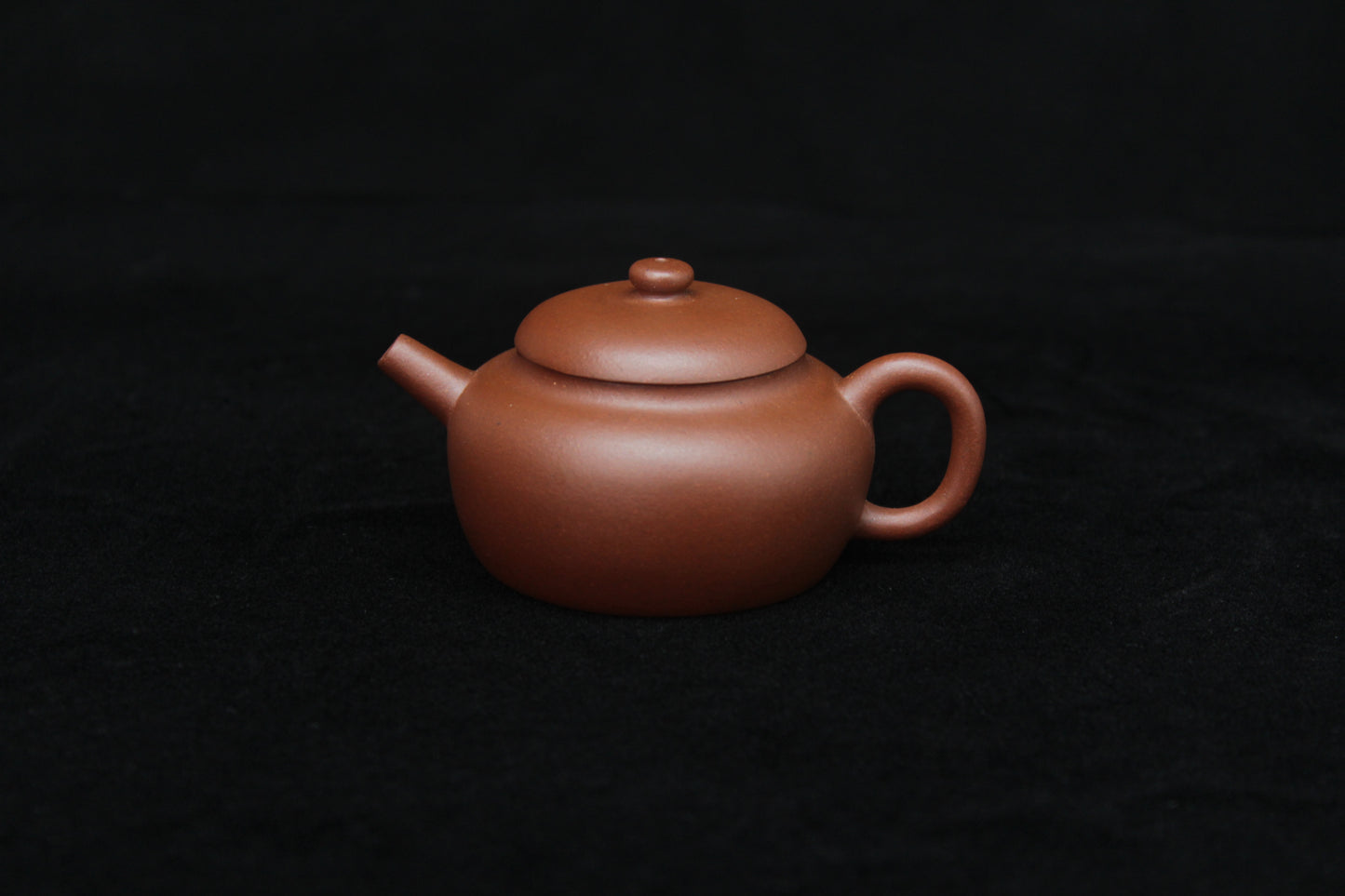 Front of a vintage small Yixing teapot made of dicaoqing purple clay