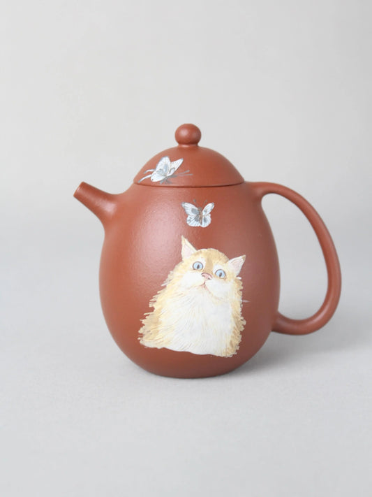 Dragon egg zisha teapot with cat painting is on the table