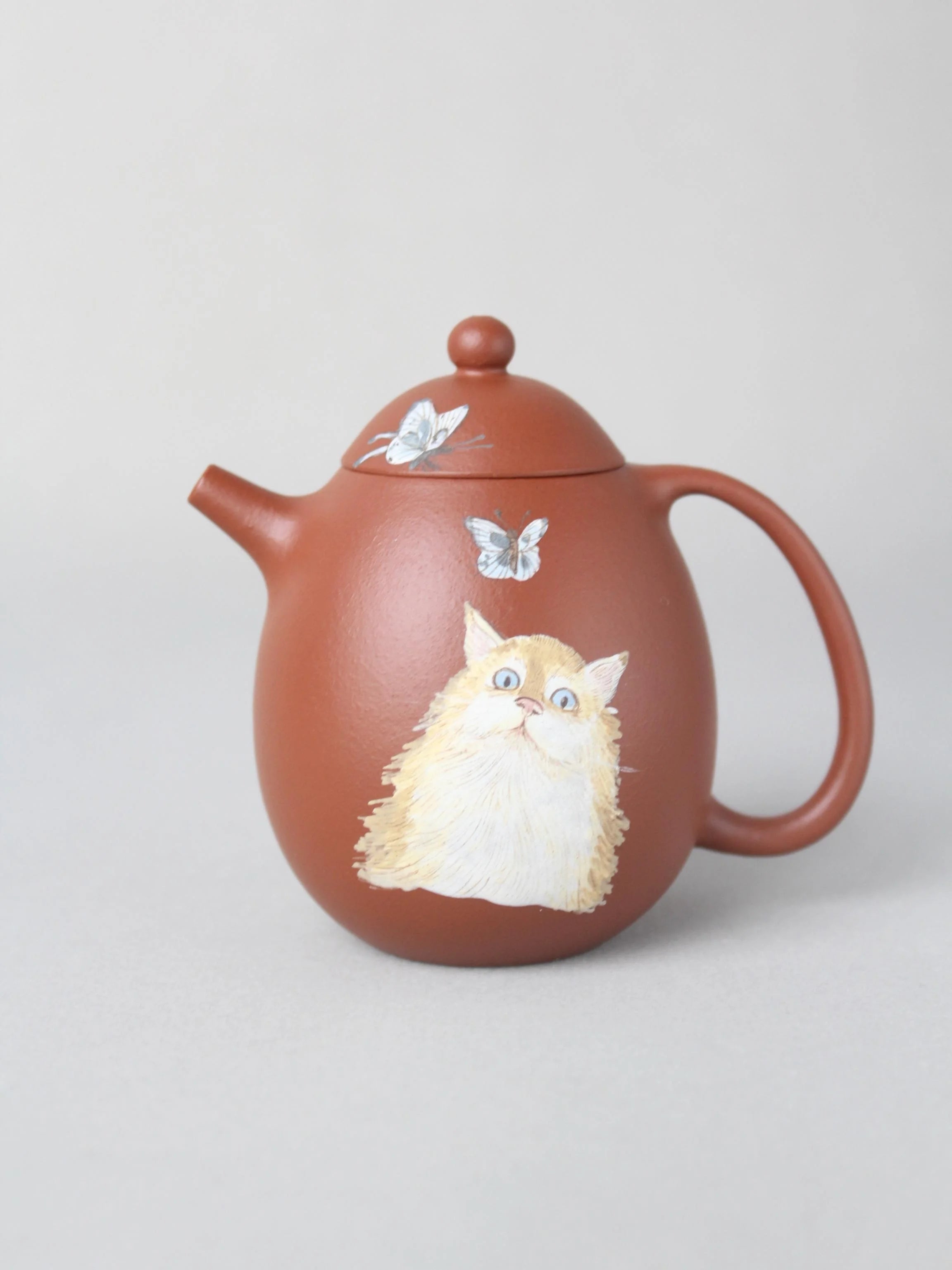 Dragon egg zisha teapot with cat painting is on the table
