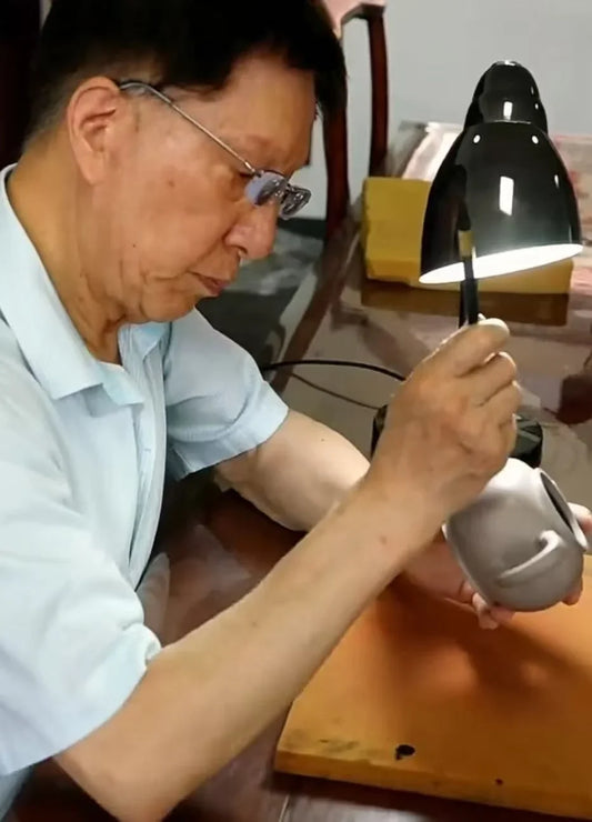Yixing teapot carving artist Zhou Boqi is carving on teapot