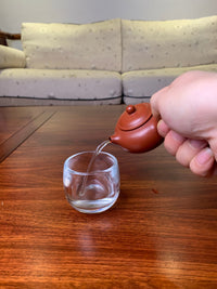 Small teapot on the table, handmade from purple clay pour