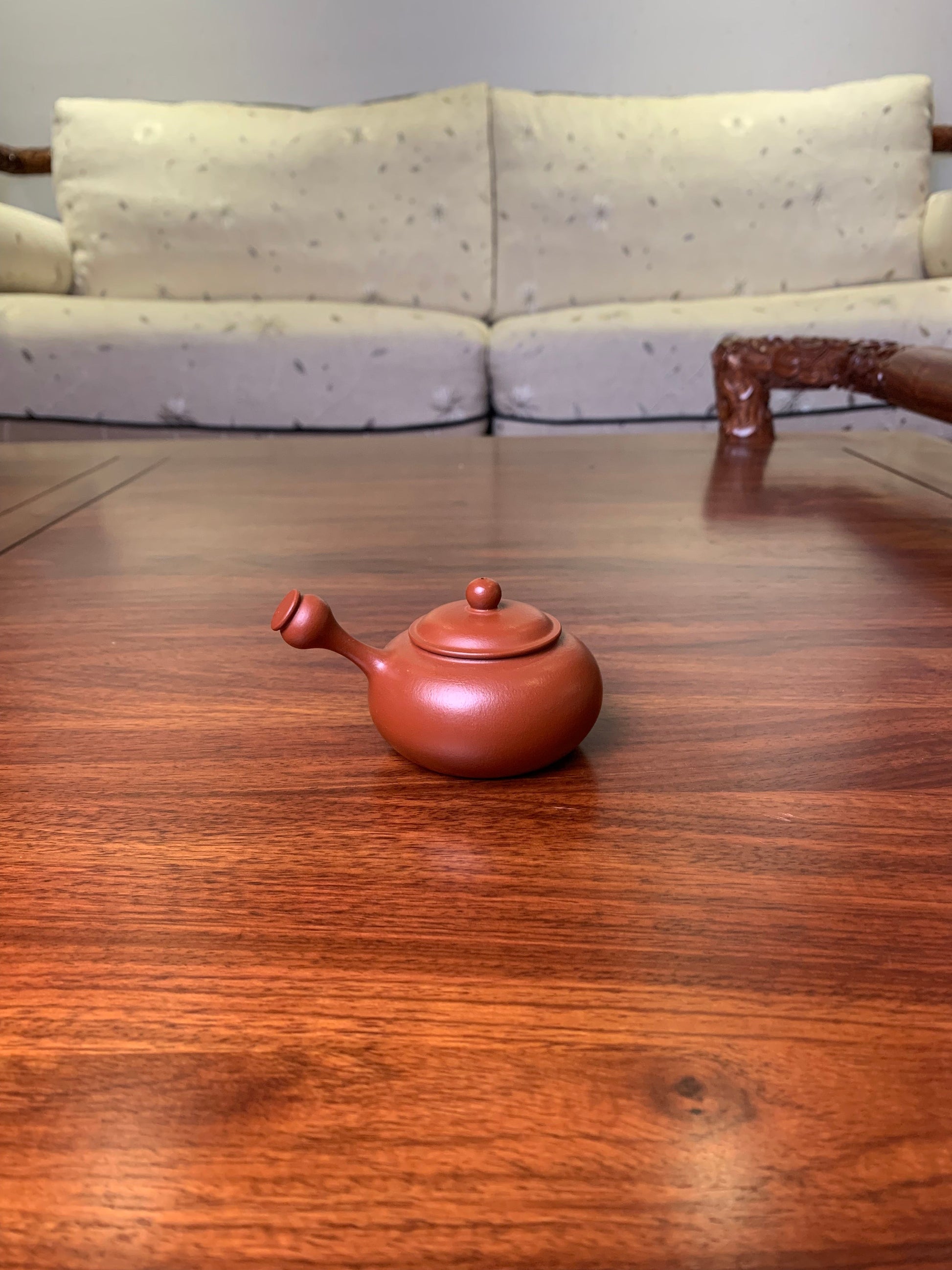 Small teapot on the table, handmade from purple clay back