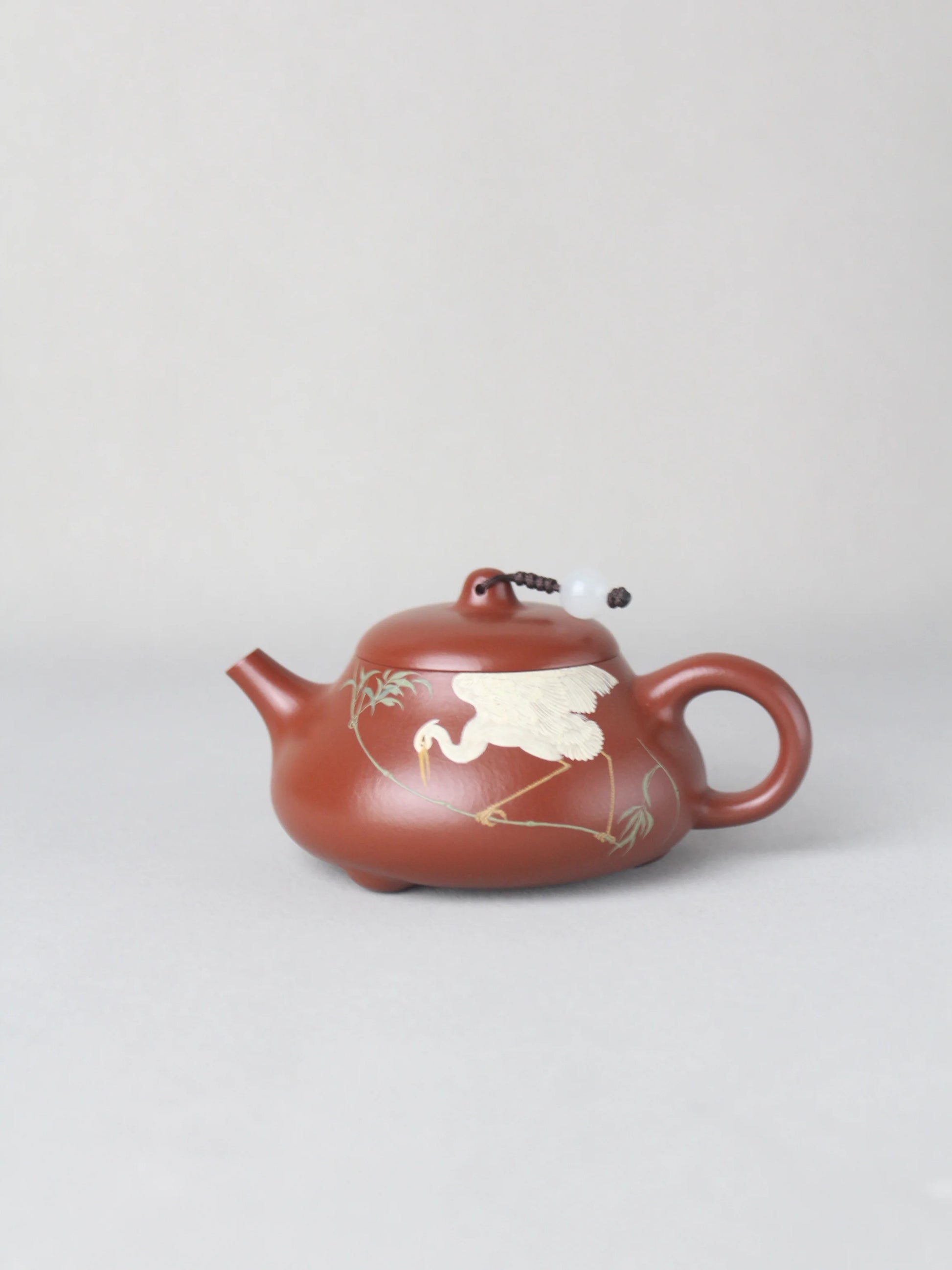 The artwork teapot named "Egret," handmade by the artist, that is on the table.