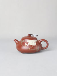 The artwork teapot named "Egret," handmade by the artist, that is on the table.