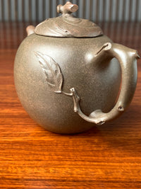 The body of the teapot is decorated with melon leaves sculpted from clay.