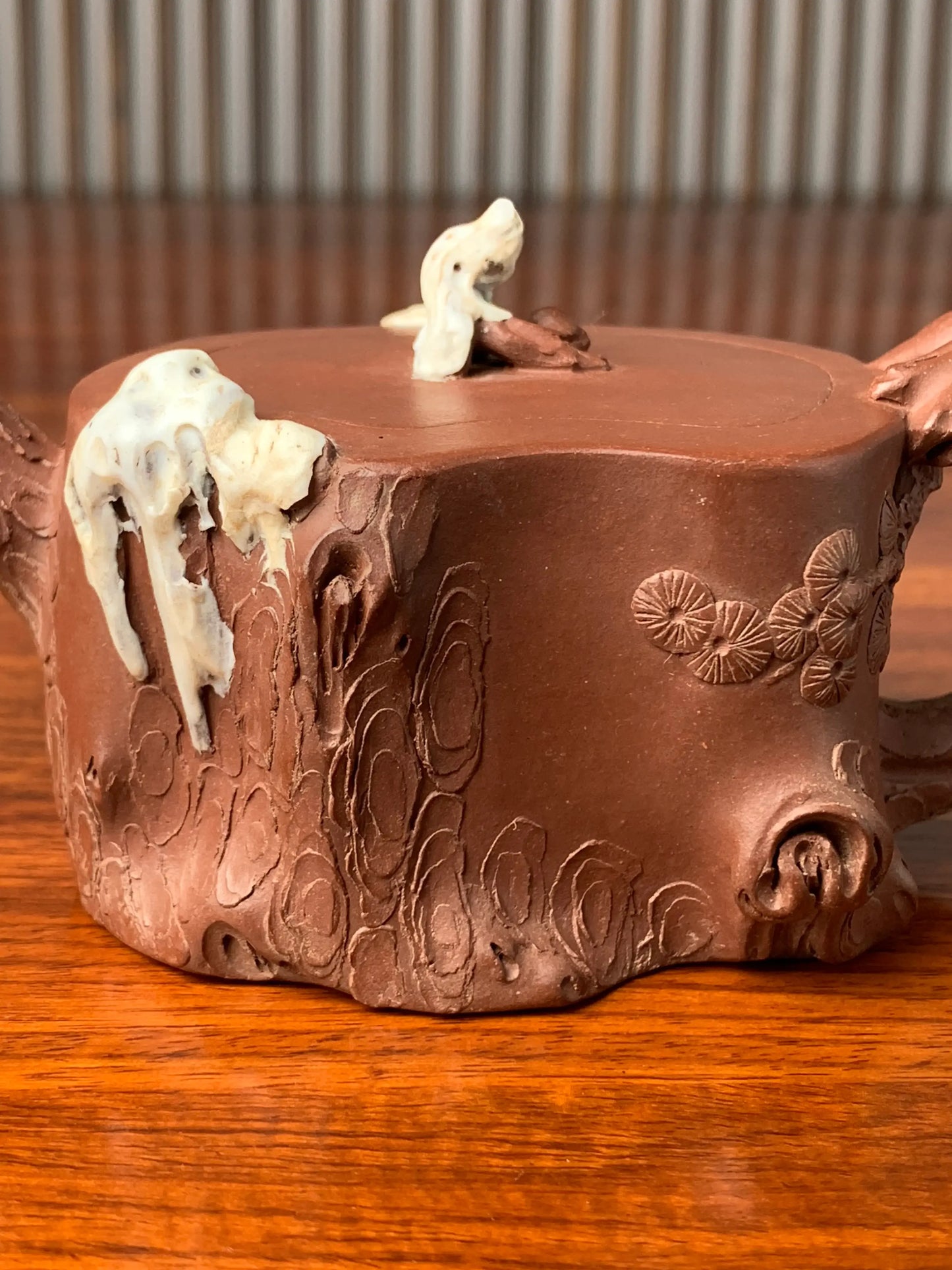 the body of the collectible teapot is decorated with a sculpture in the shape of a pine tree