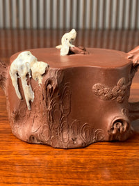 the body of the collectible teapot is decorated with a sculpture in the shape of a pine tree