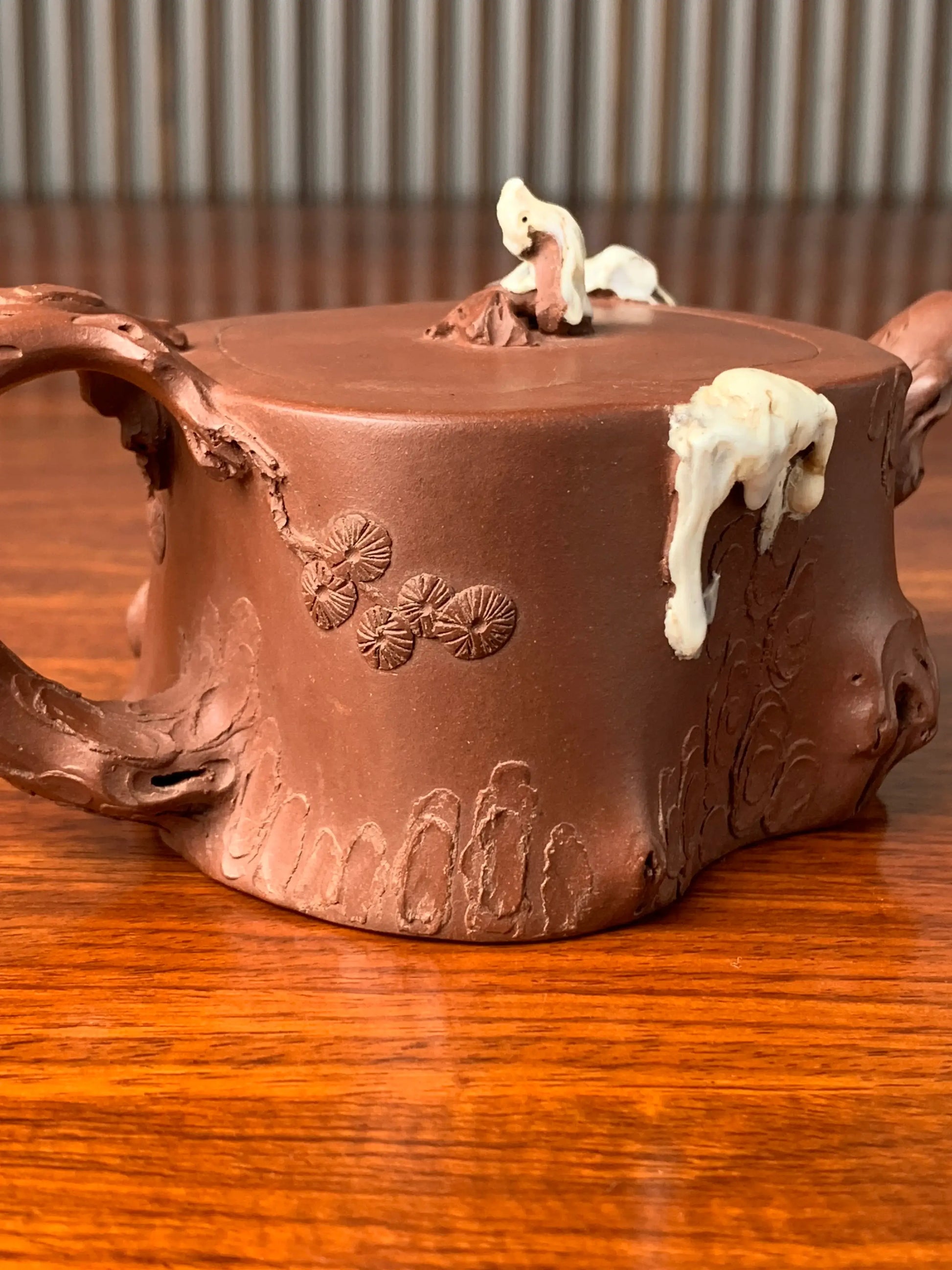 the body of the collectible teapot is decorated with a sculpture in the shape of a pine tree right view