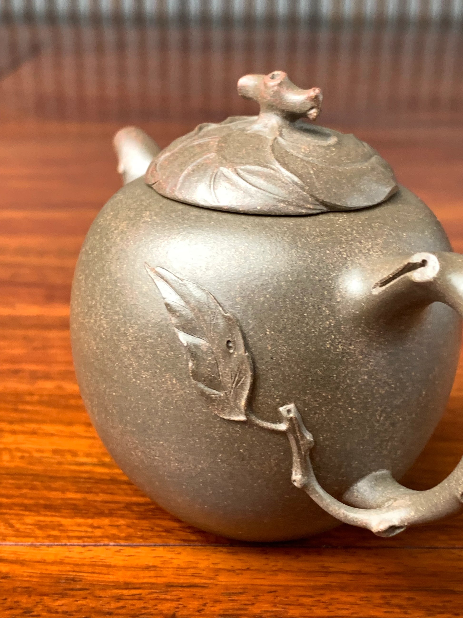 A close-up photo of the teapot adorned with clay-sculpted melon leaves.