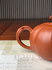 the handle of the teapot is shaped like a pumpkin vine