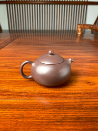 the back view of handmade yixing teapot named xi shi on the table