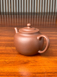 side view of handmade yixing teapot named ping gai lian zi on the table