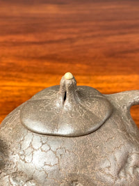 The knob of this teapot is shaped like a plant stem