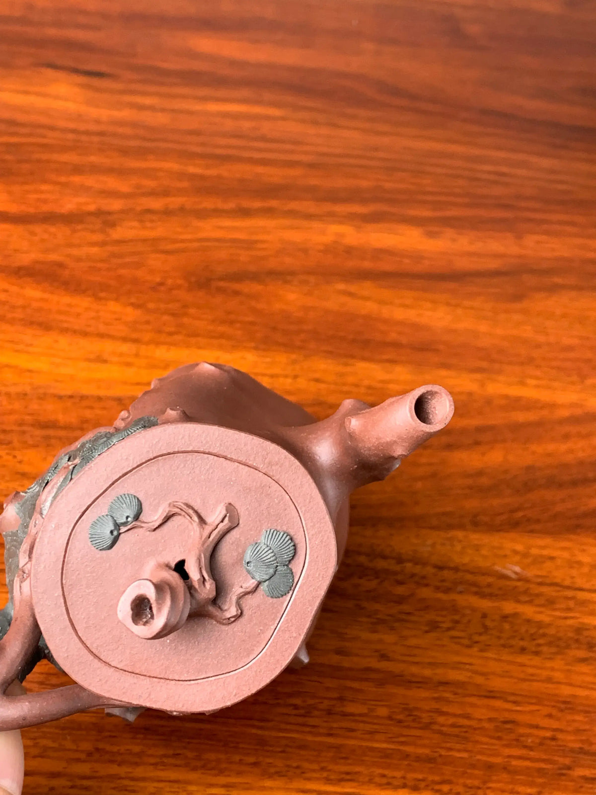 Top-down view of the pine branch design details on the teapot lid knob.