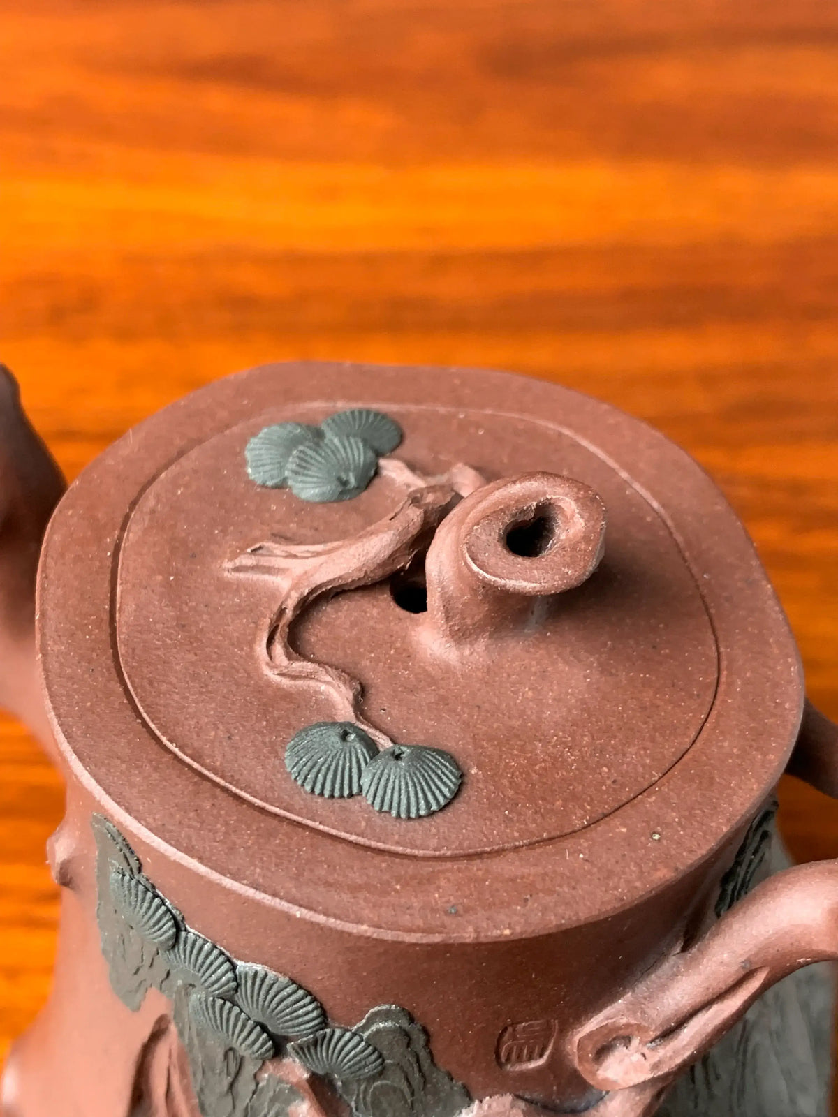 Close-up of the pine branch design details on the teapot lid knob