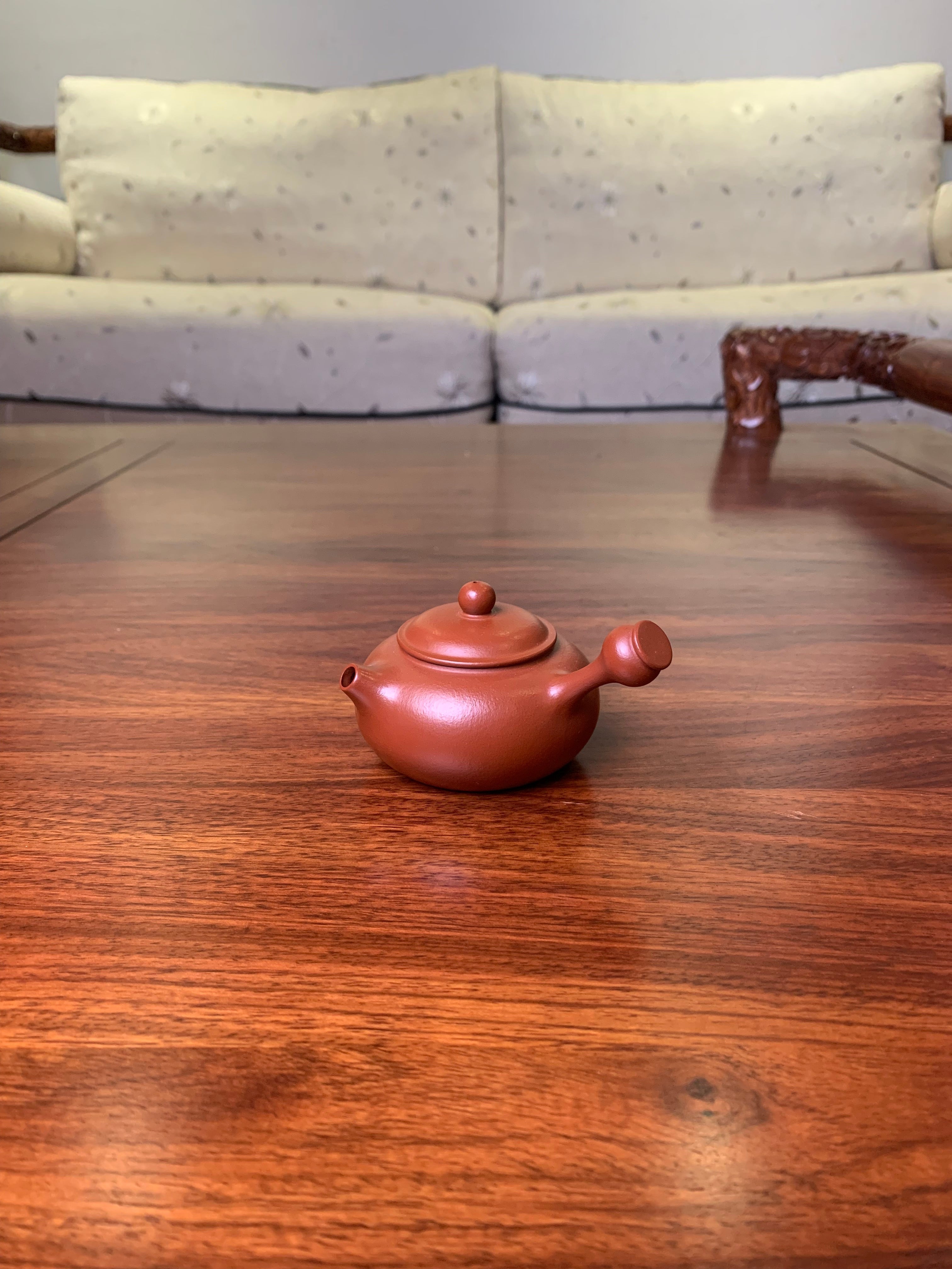 Small teapot on the table, handmade from purple clay