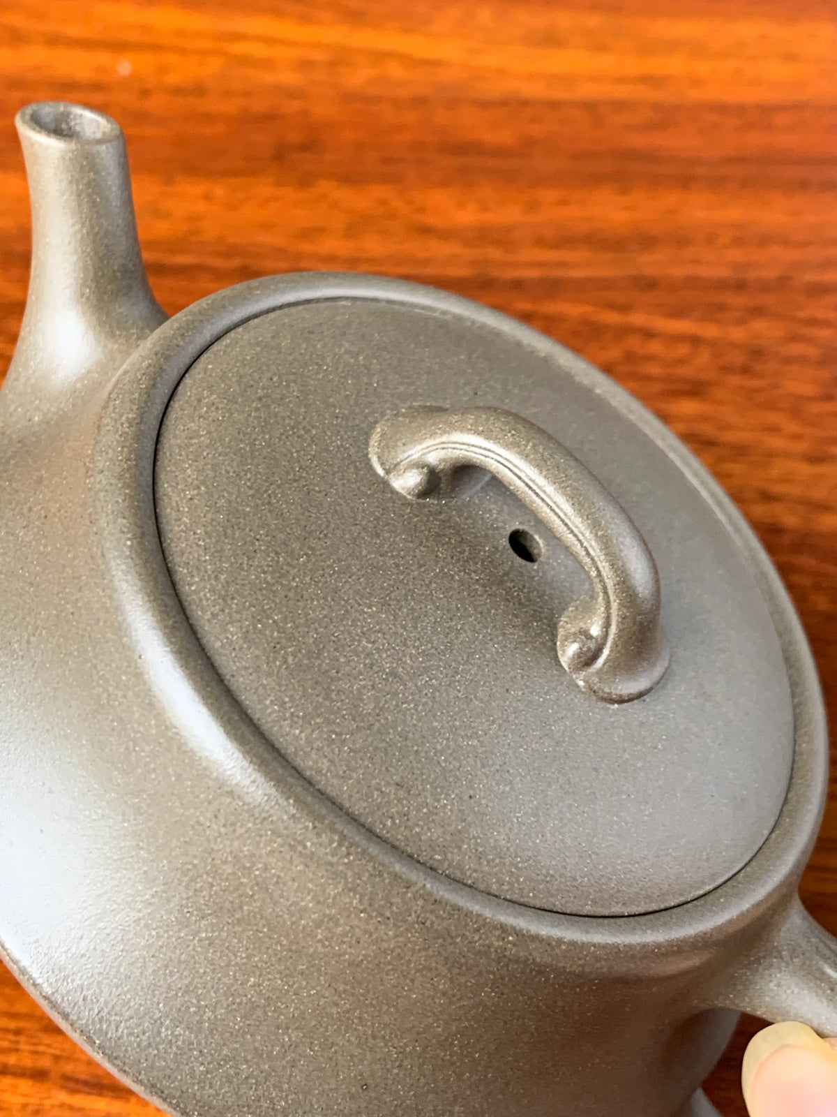 Viewed from the side, the lid knob and lid of a finely crafted teapot.