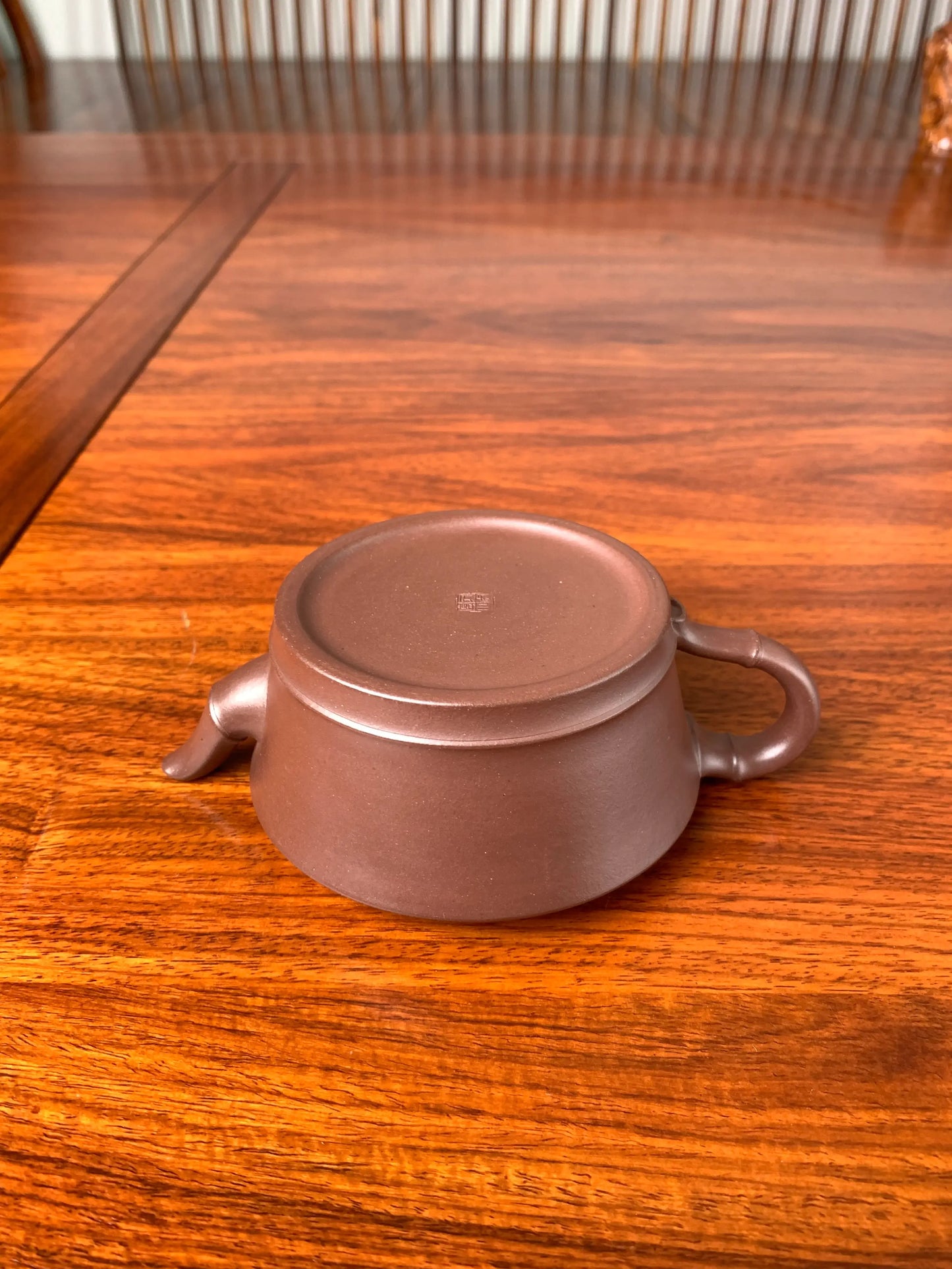The teapot turned upside down on the table, revealing the fine craftsmanship around the base