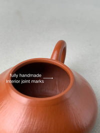 The seam traces resulting from the full handmade construction, visible on the interior surface of the teapot.