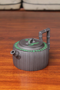 Front of  the vintage teapot handmade with purple clay on the table