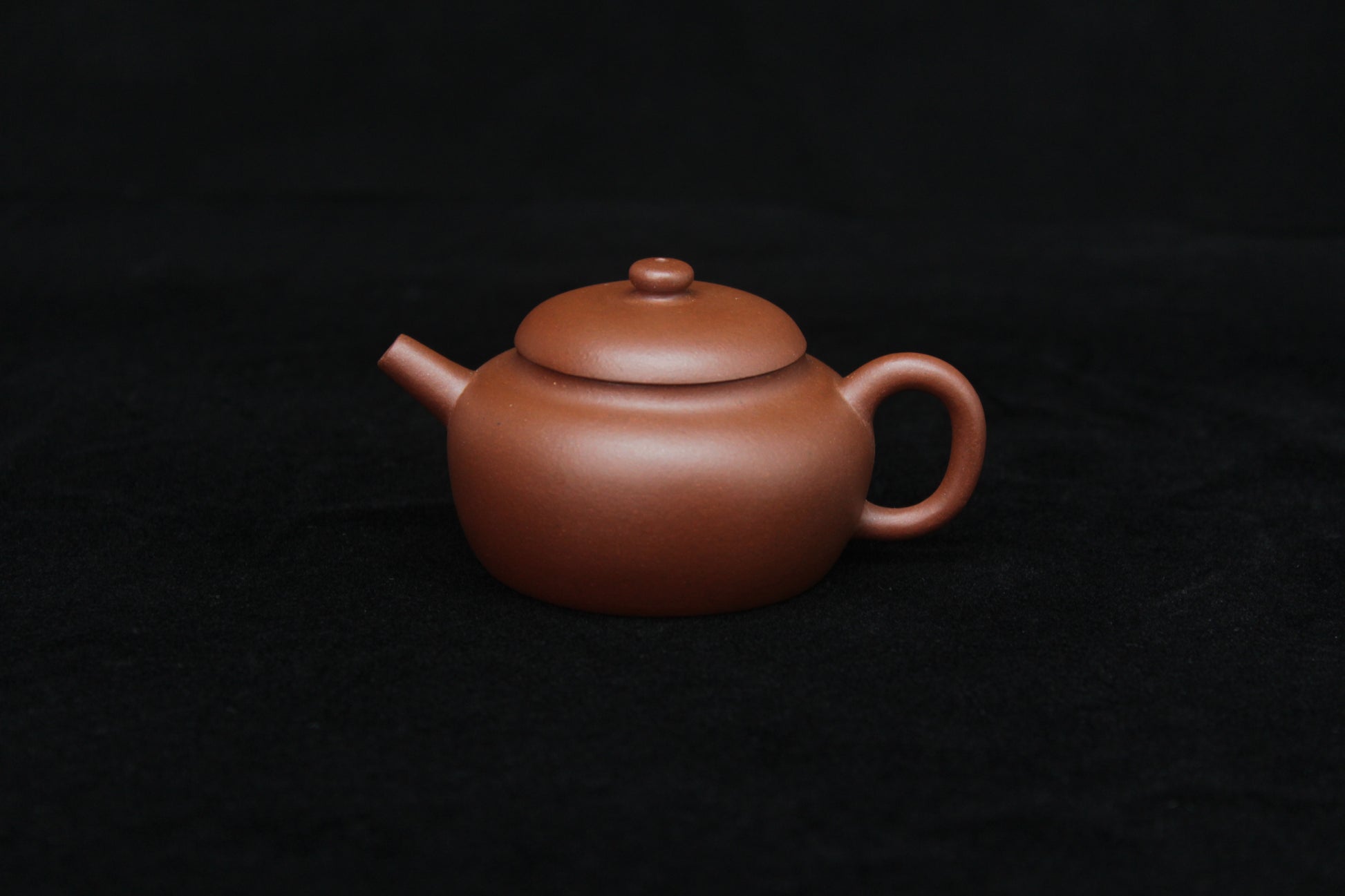 Front of a vintage small Yixing teapot made of dicaoqing purple clay