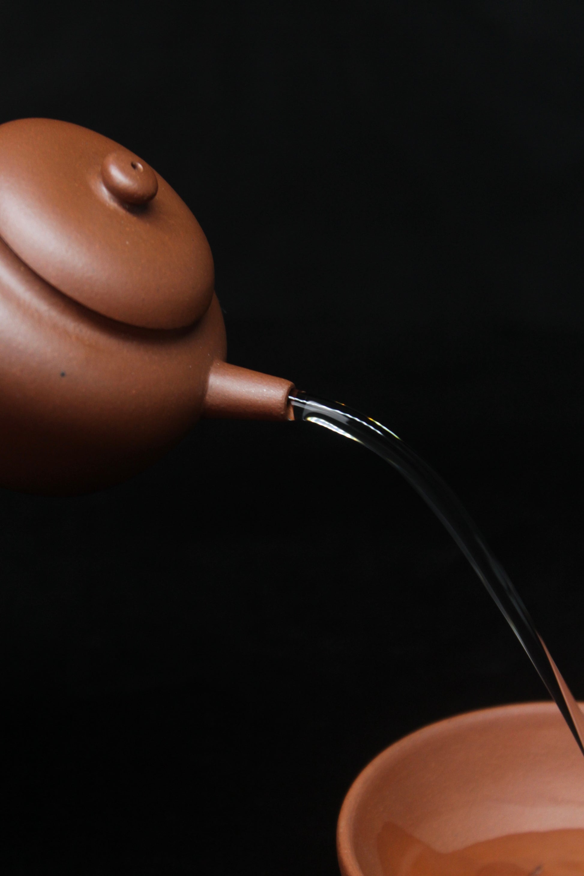 Pour of a vintage small Yixing teapot made of dicaoqing purple clay.