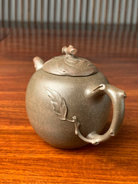 A photo of the teapot decorated with melon leaves sculpted from clay.