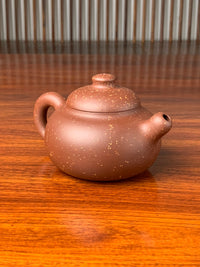 the left view of the yixing zisha clay teapot on the table